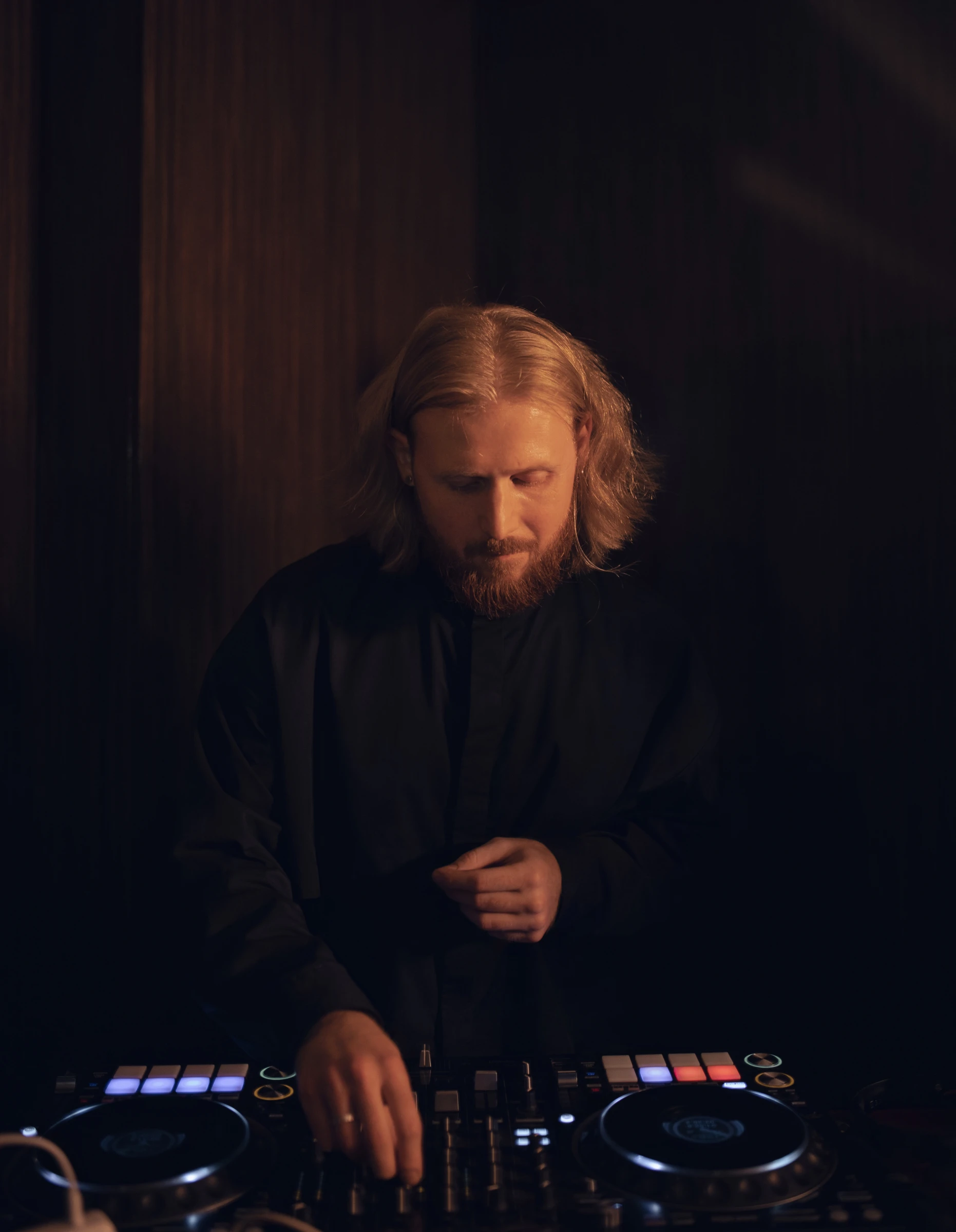 Диджей работает за пультом Pioneer в тёплом свете вечернего зала