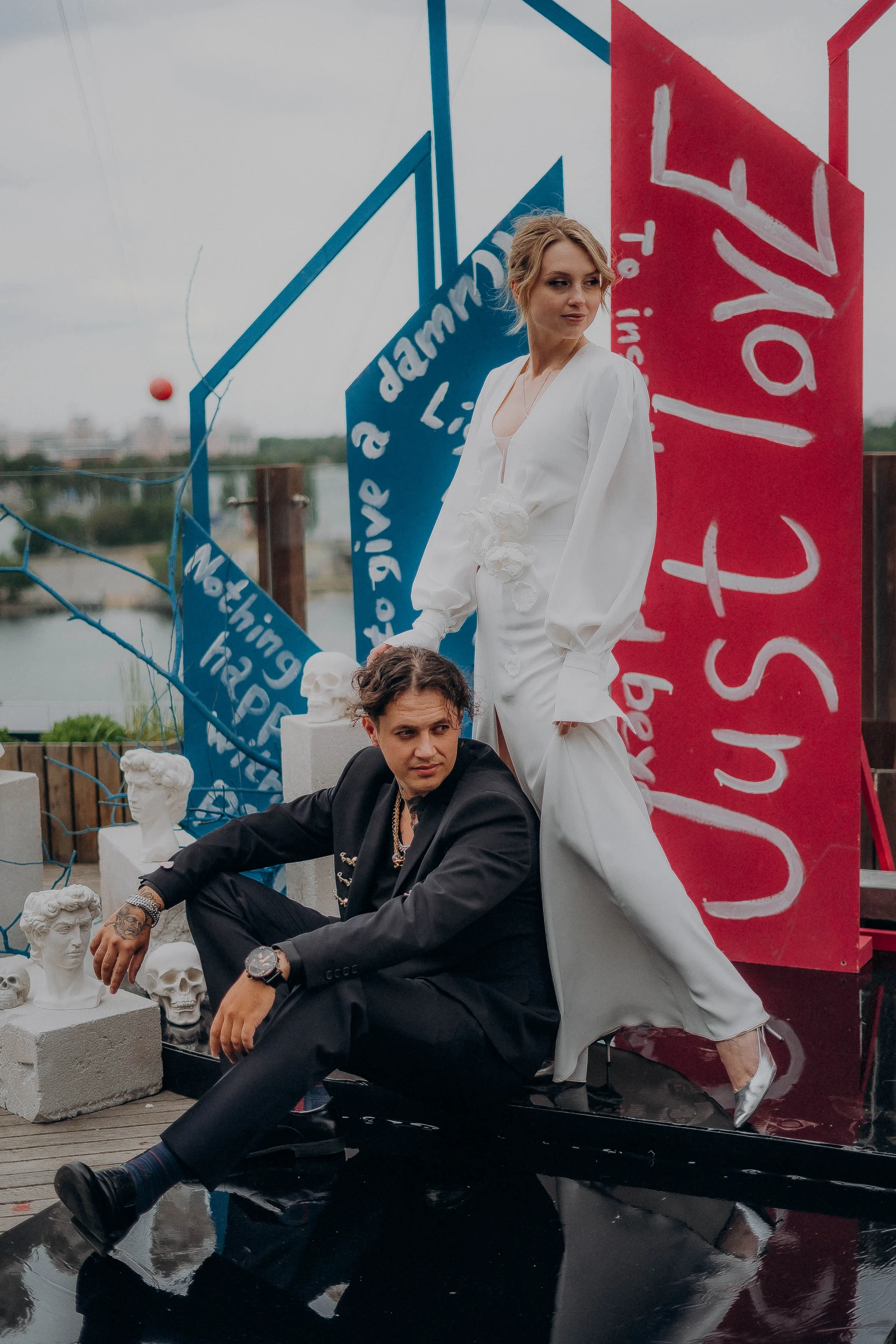 невеста и жених позируют у арт-объекта с надписью Just Love на крыше