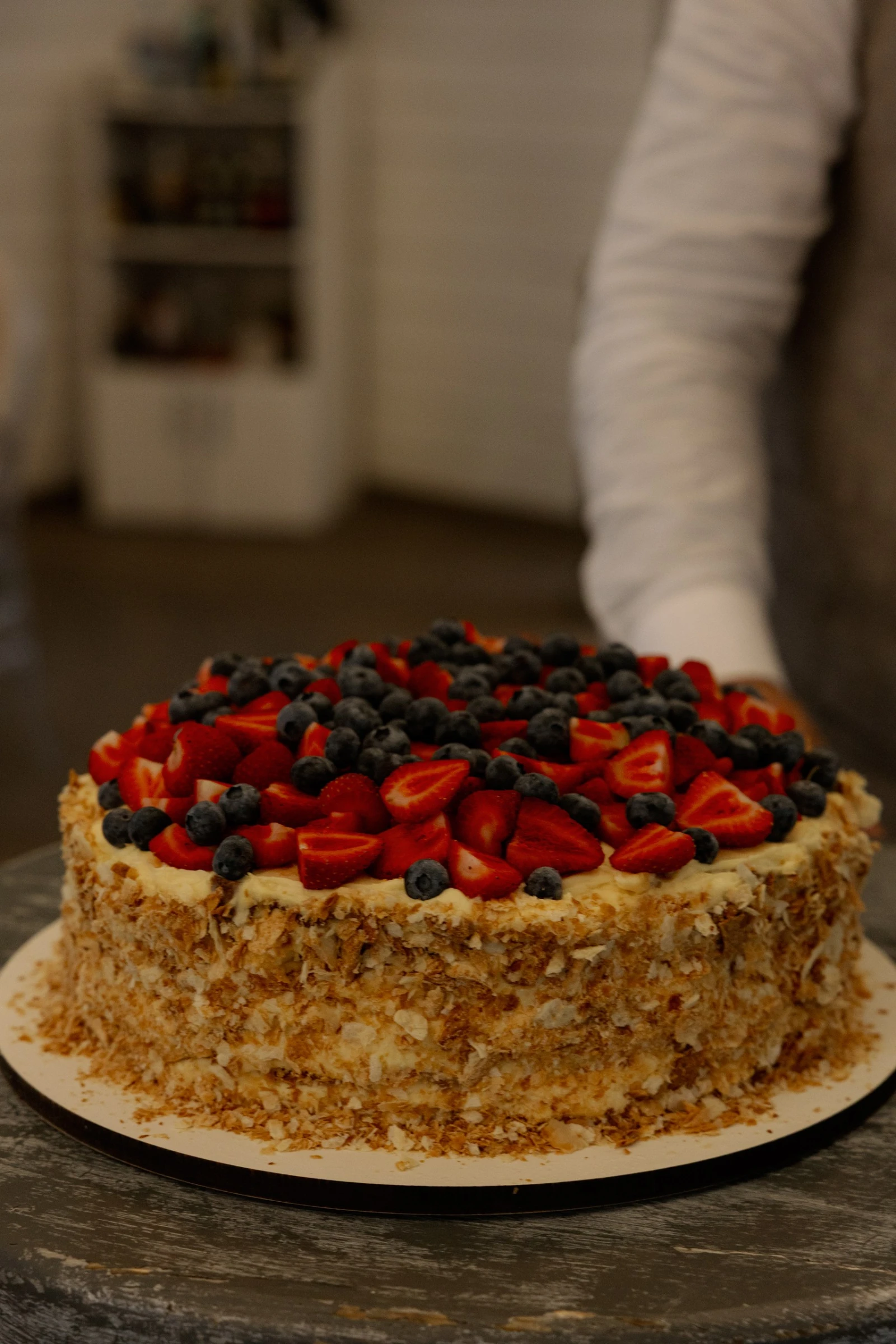 круглый торт с клубникой черникой и ореховой крошкой на деревянном столе