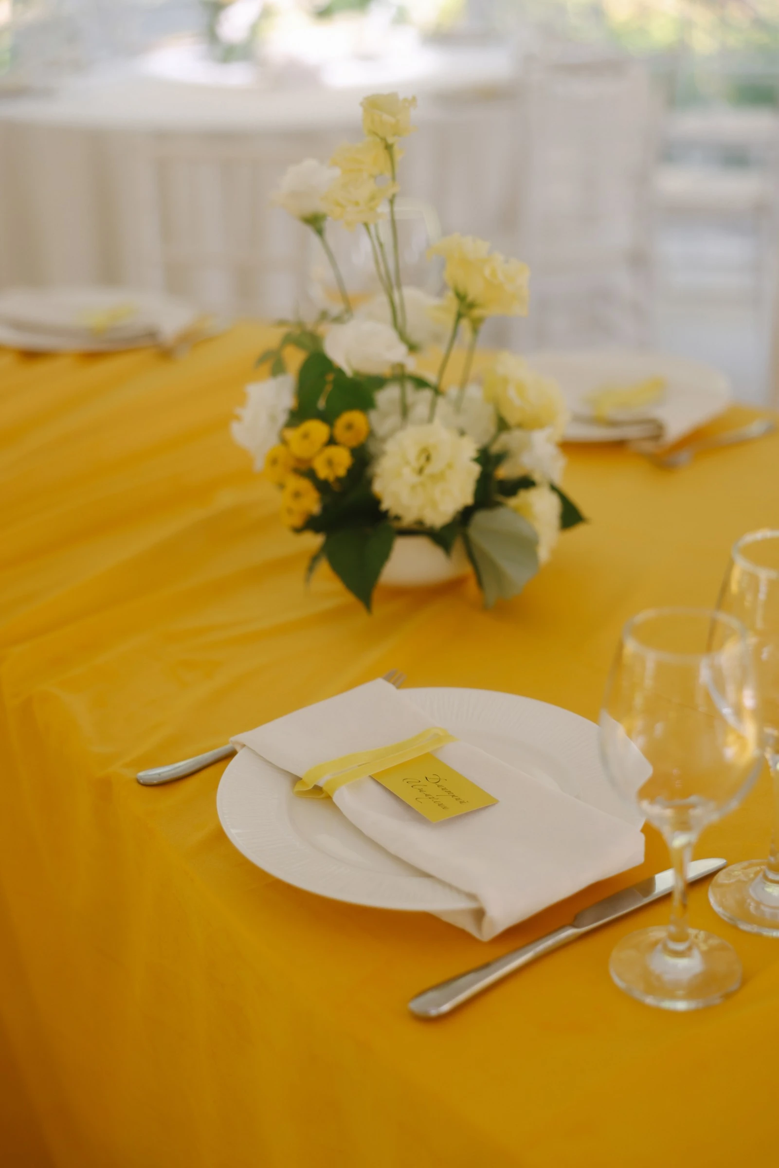Сервировка стола с белой тарелкой и жёлтой скатертью на банкете в шатре