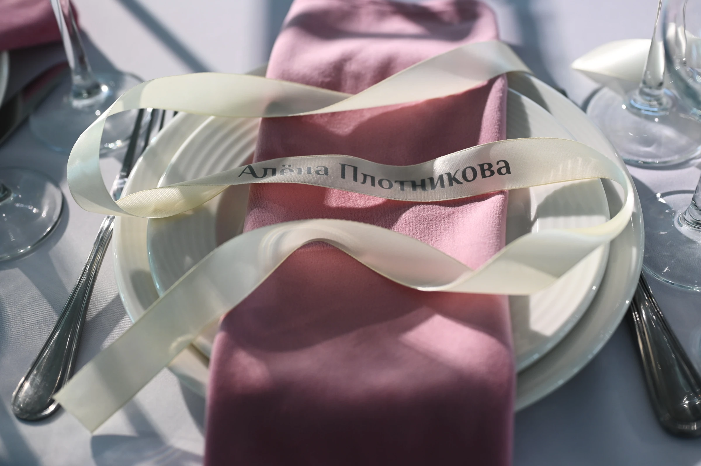 рассадочная карточка на розовой салфетке с атласной лентой на столе