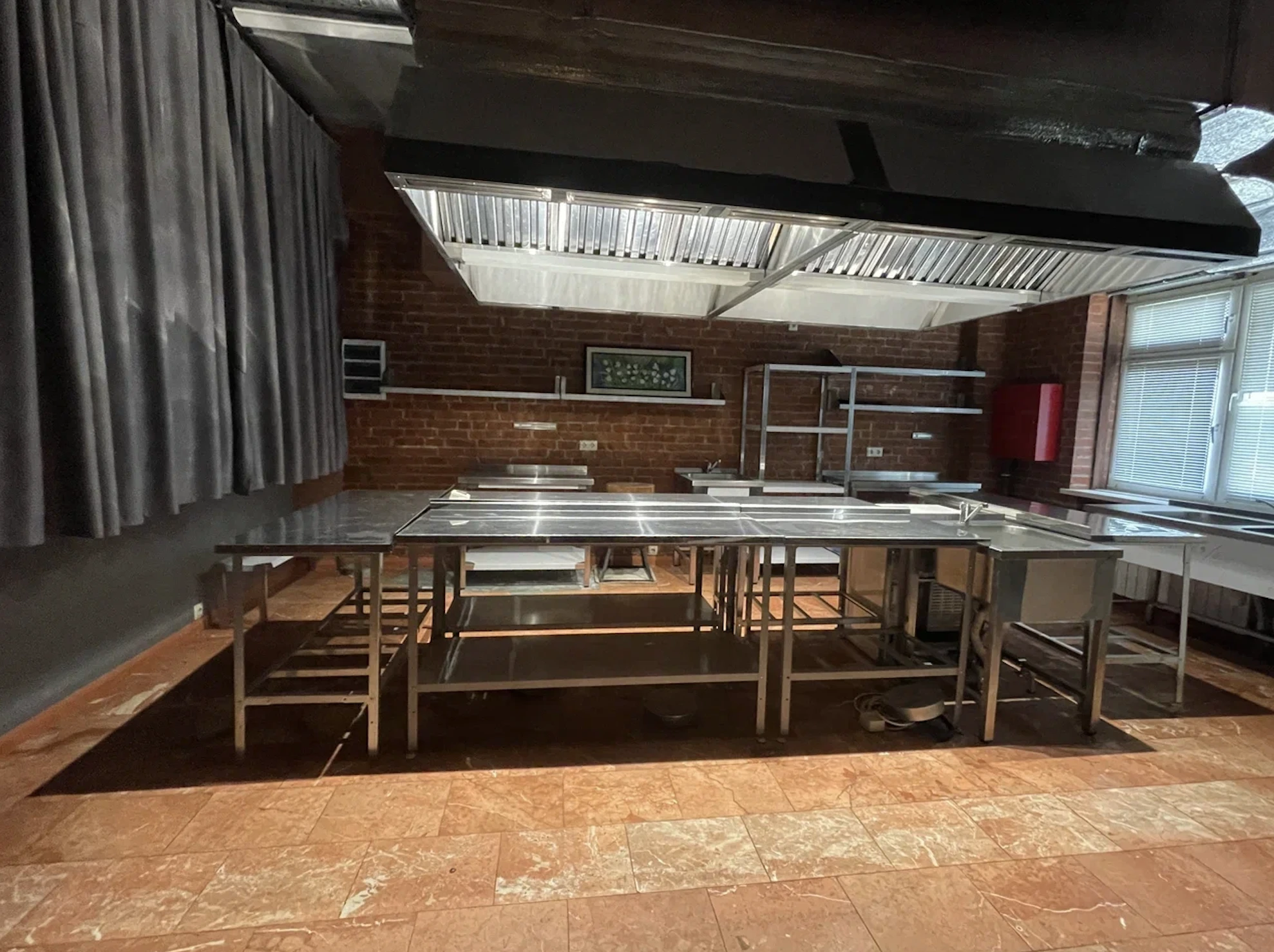 кейтеринговая кухня с металлическими столами и вытяжкой на площадке в стиле лофт