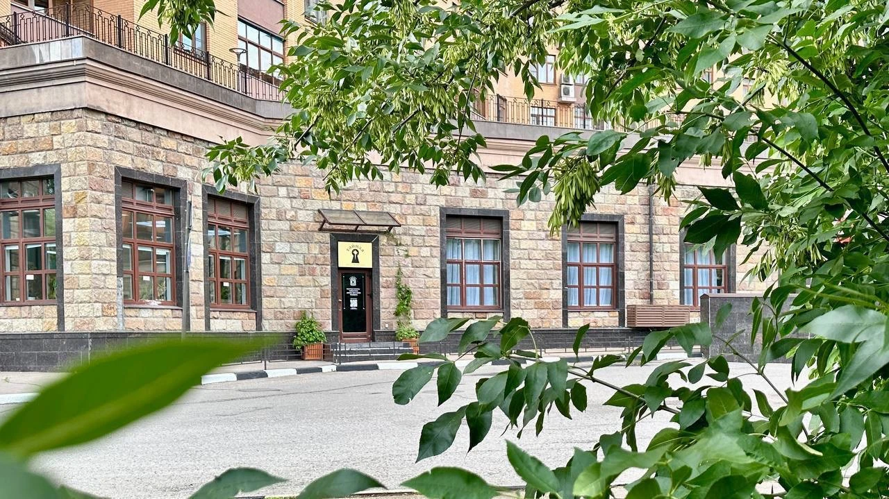 каменный фасад здания площадки с арочными окнами и зеленью