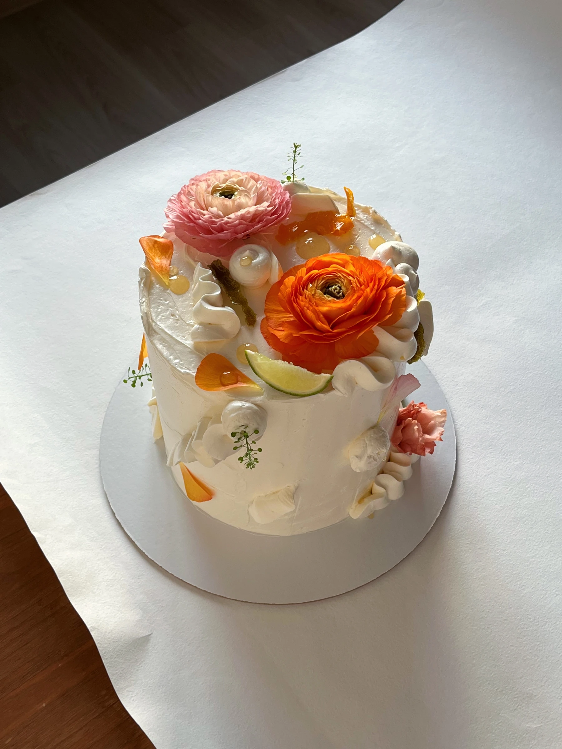 торт с розовыми ранункулюсами лаймом и безе-ракушками в студийной съемке