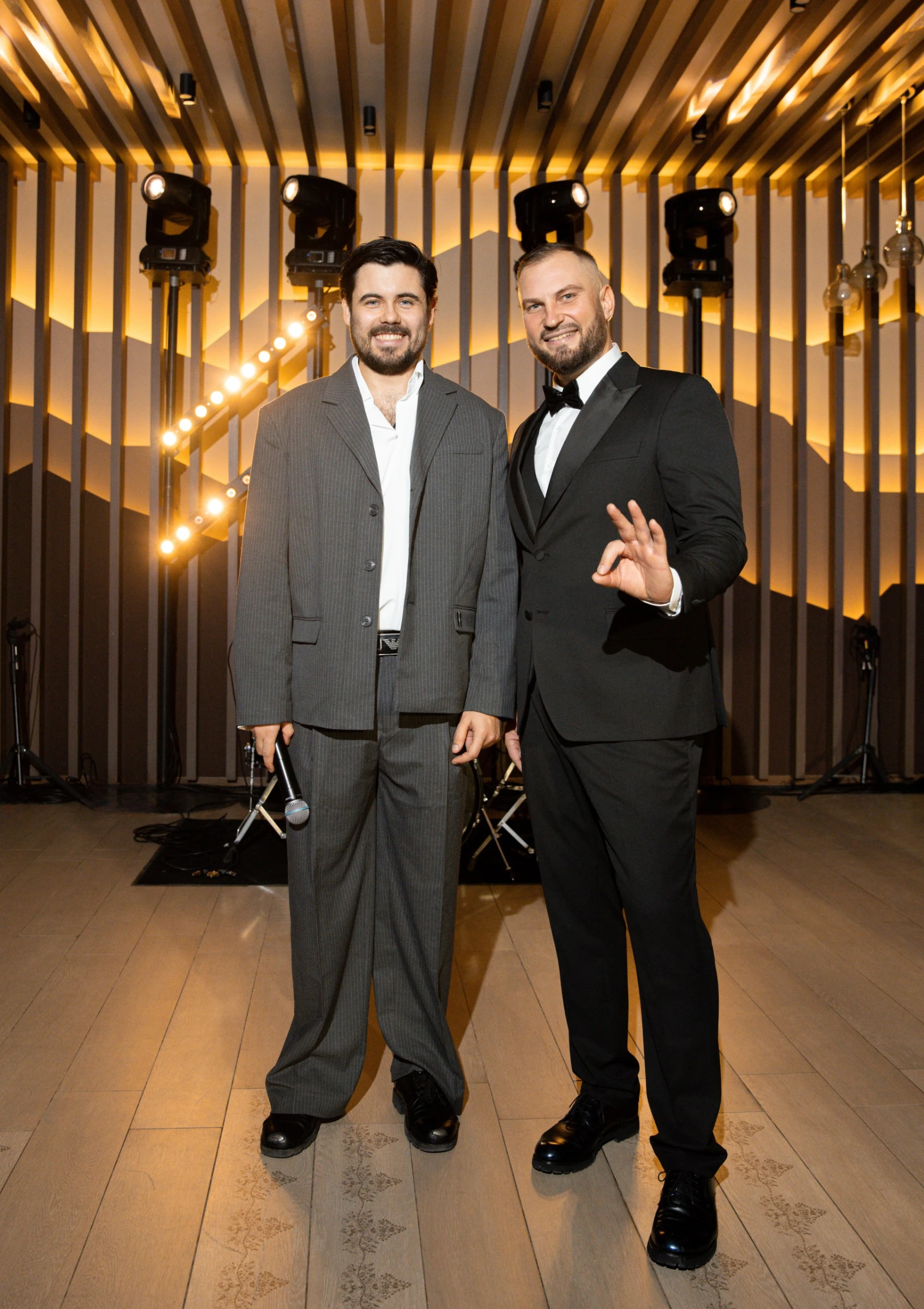 ведущий с гостем в костюмах на подсвеченной сцене банкетного зала