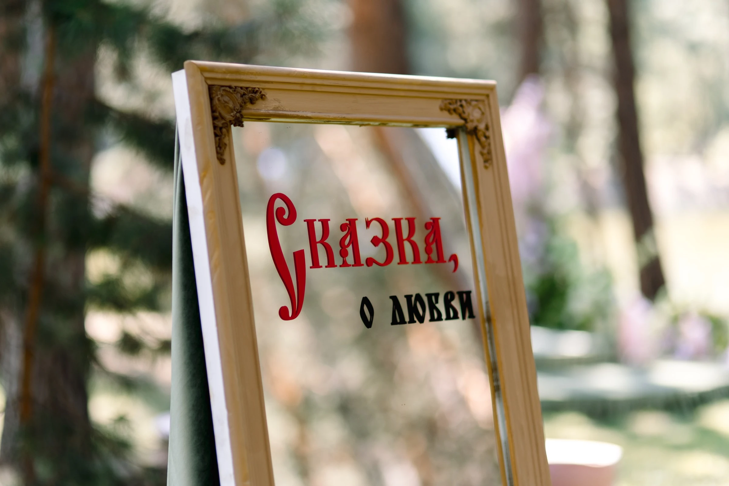 зеркальная табличка в деревянной раме с надписью о любви в саду
