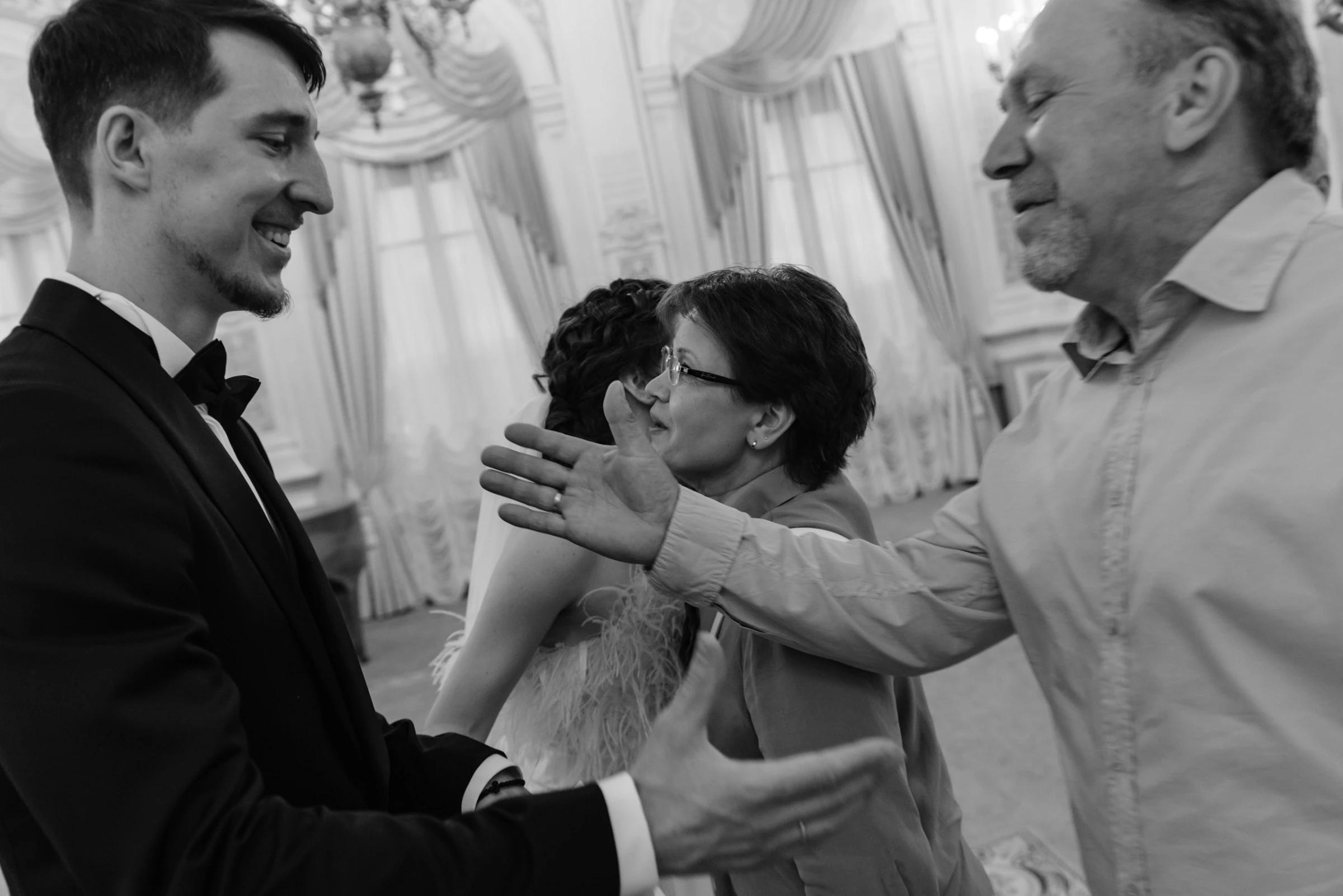 Жених обнимает родителей на свадебном банкете в зале