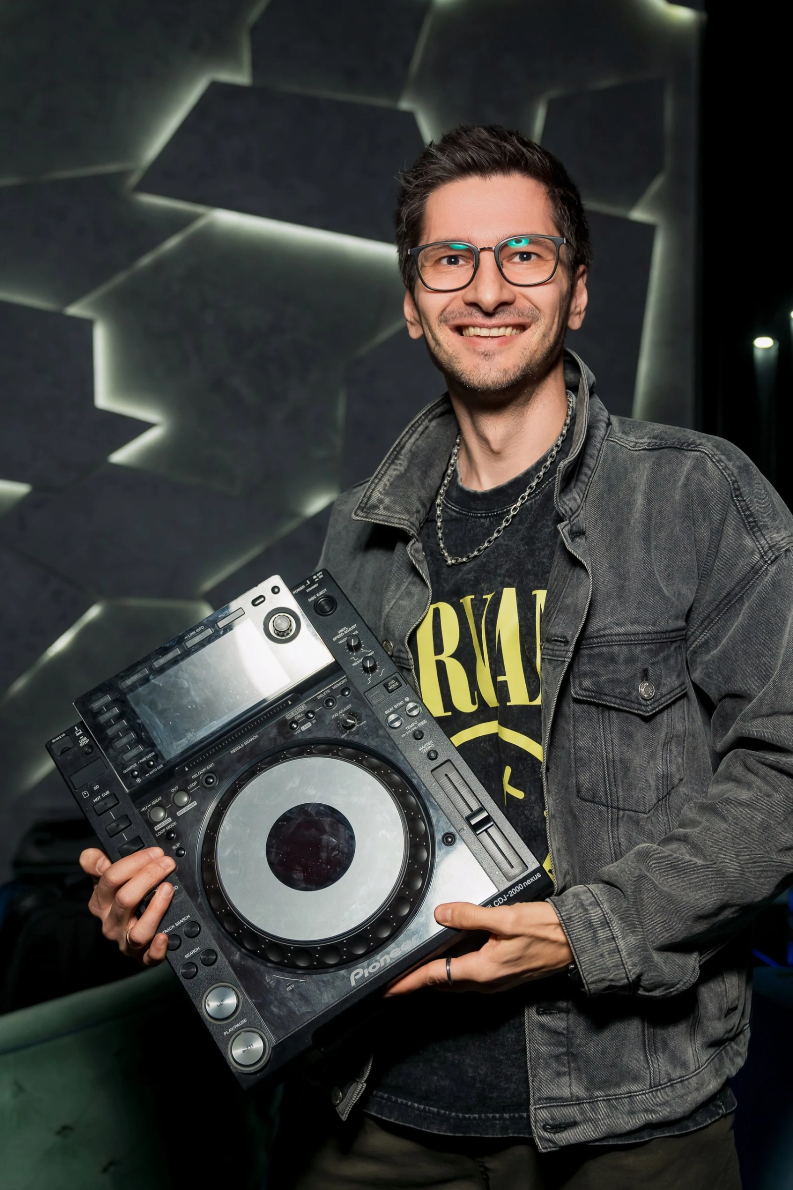 диджей держит проигрыватель pioneer на фоне тёмной подсветки