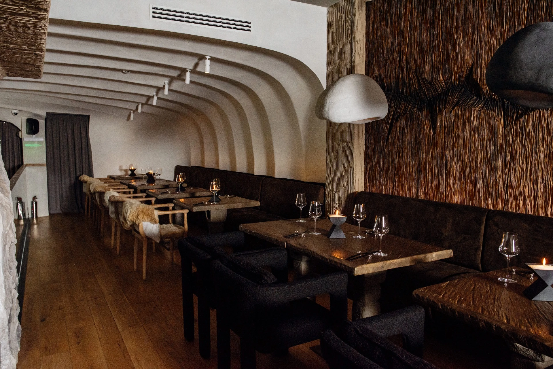 ряд столиков со свечами вдоль изогнутой сводчатой стены в тёплом приглушённом освещении