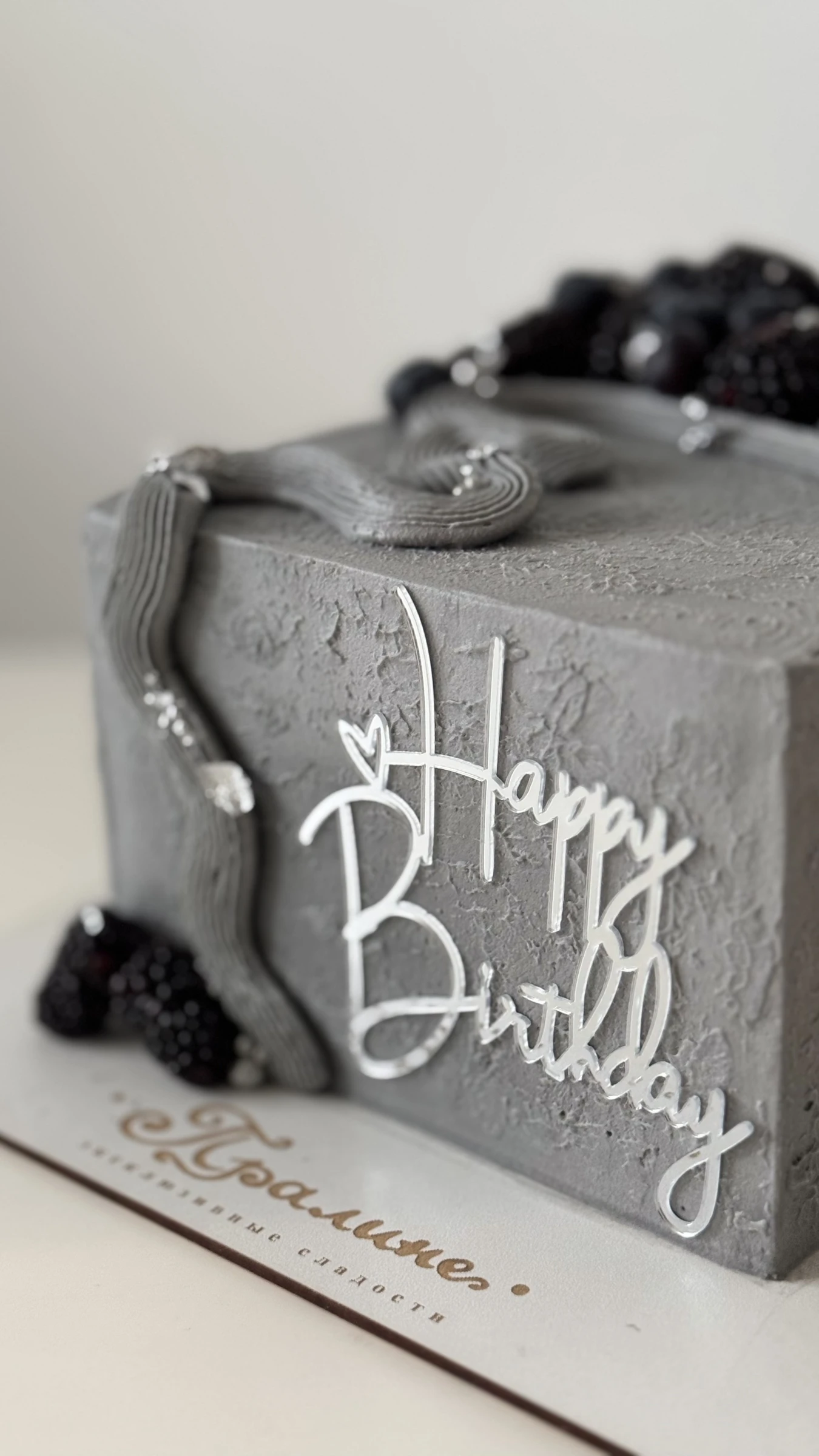 серый текстурный торт украшен ежевикой серебряной цепочкой и топпером happy birthday