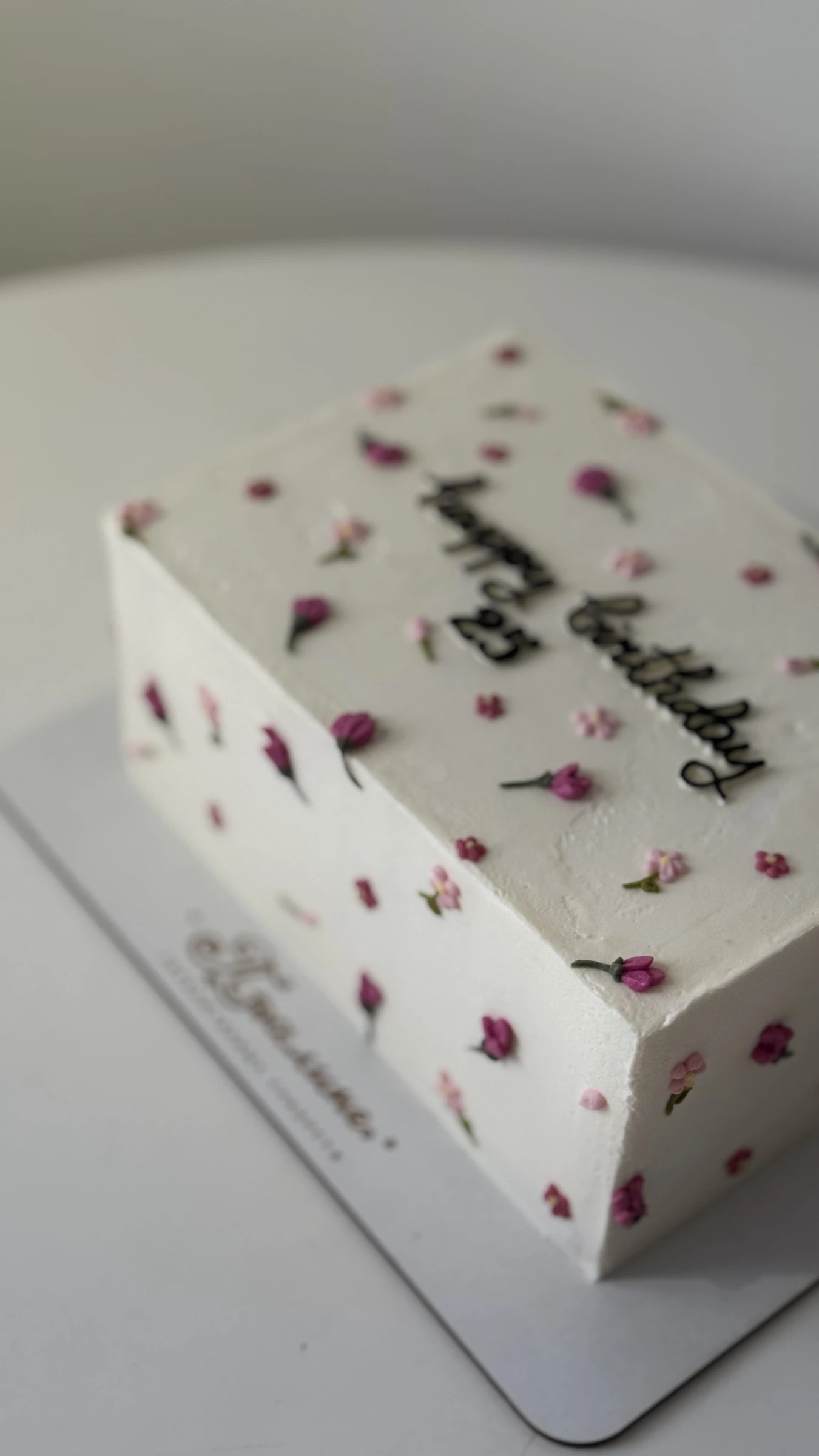 белый торт с мелкими розовыми цветами и надписью happy birthday крупным планом