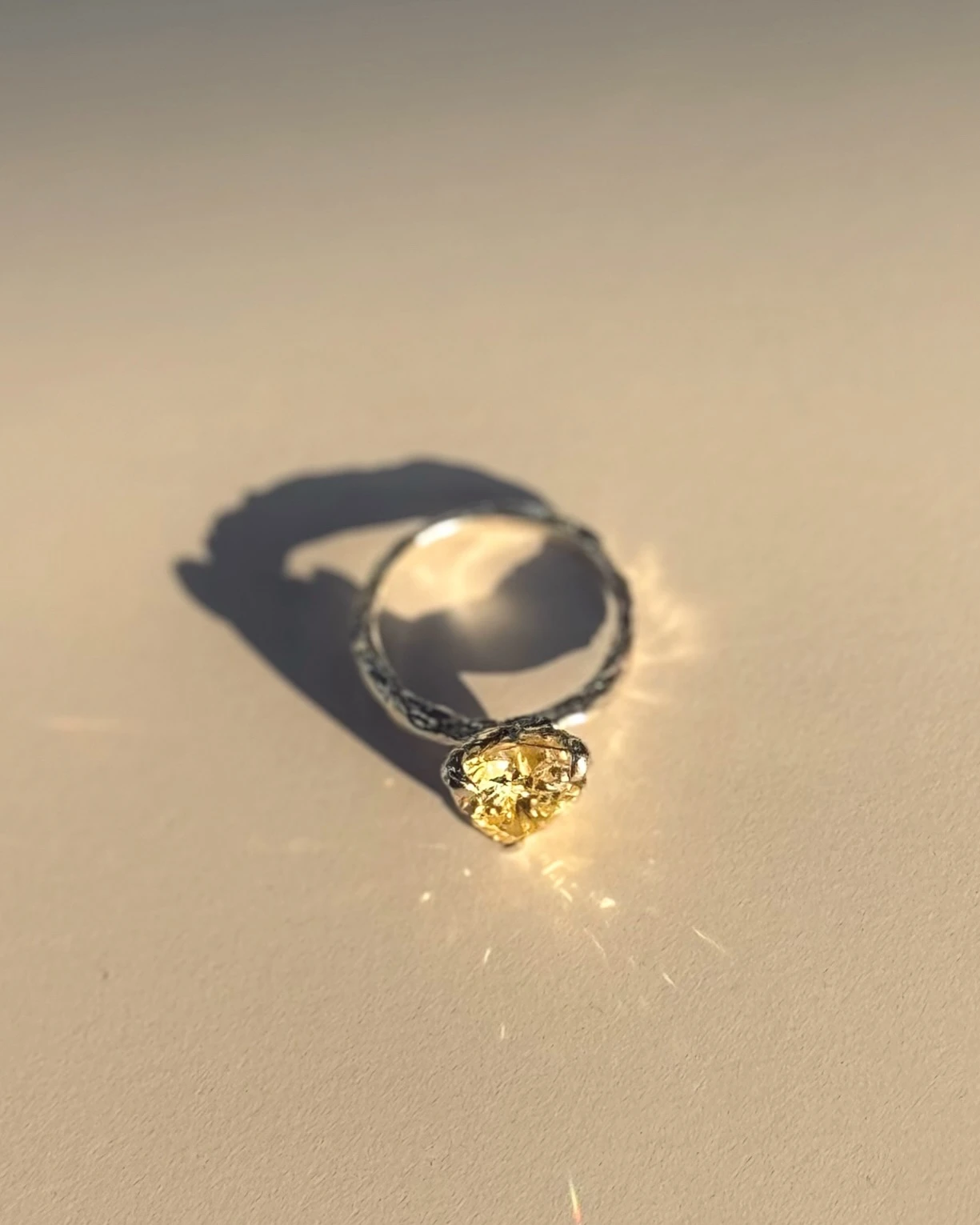 серебряное кольцо с жёлтым камнем в фигурной оправе на светлом фоне