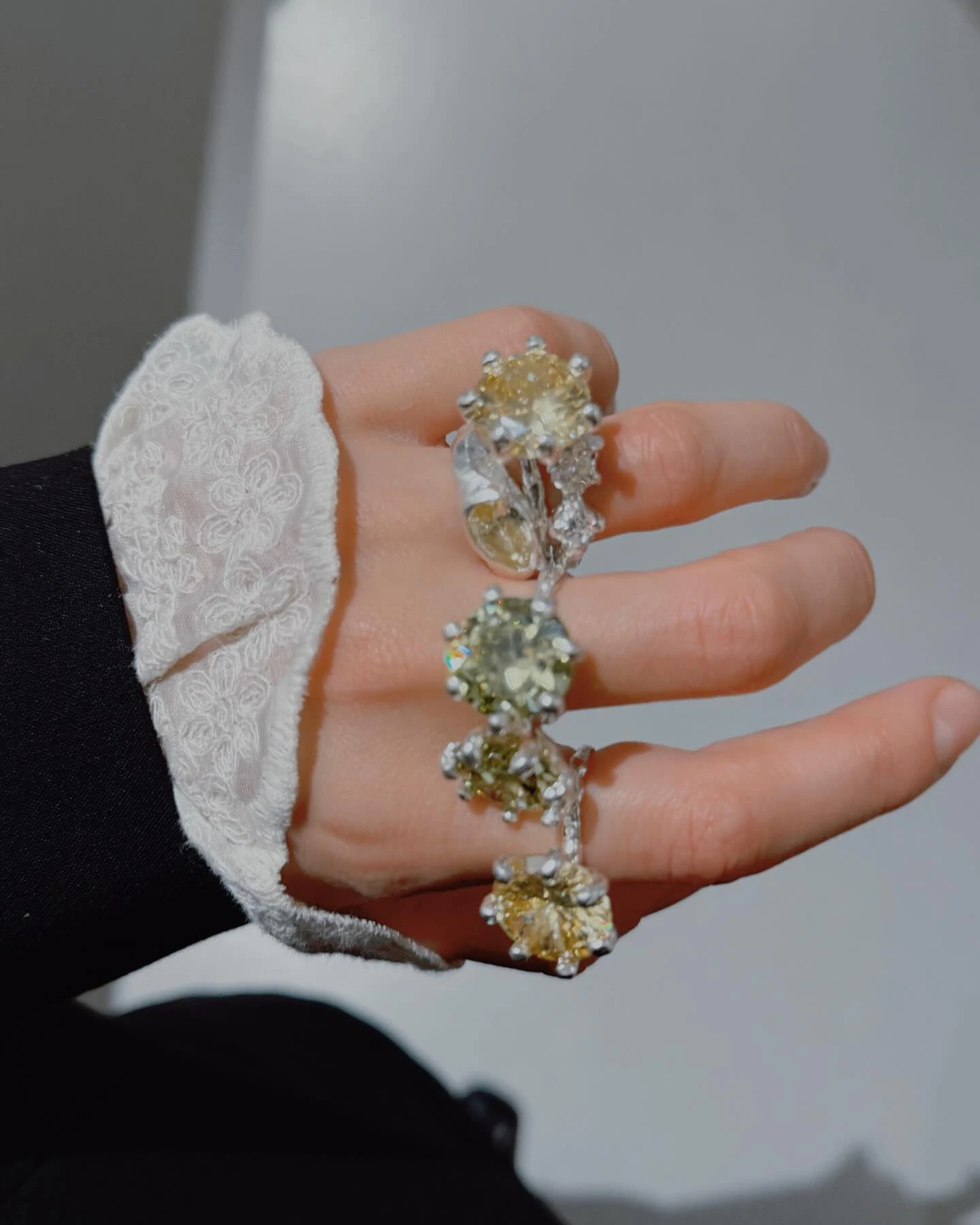 серебряные кольца с жёлтыми камнями на пальцах руки в кружевном рукаве