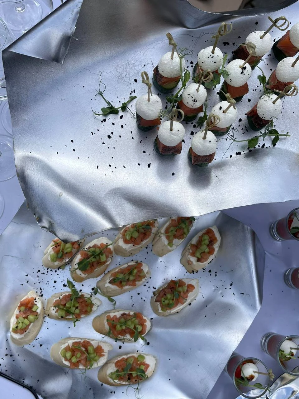 Канапе с лососем и брускетты на мятой серебристой фольге на банкетном столе