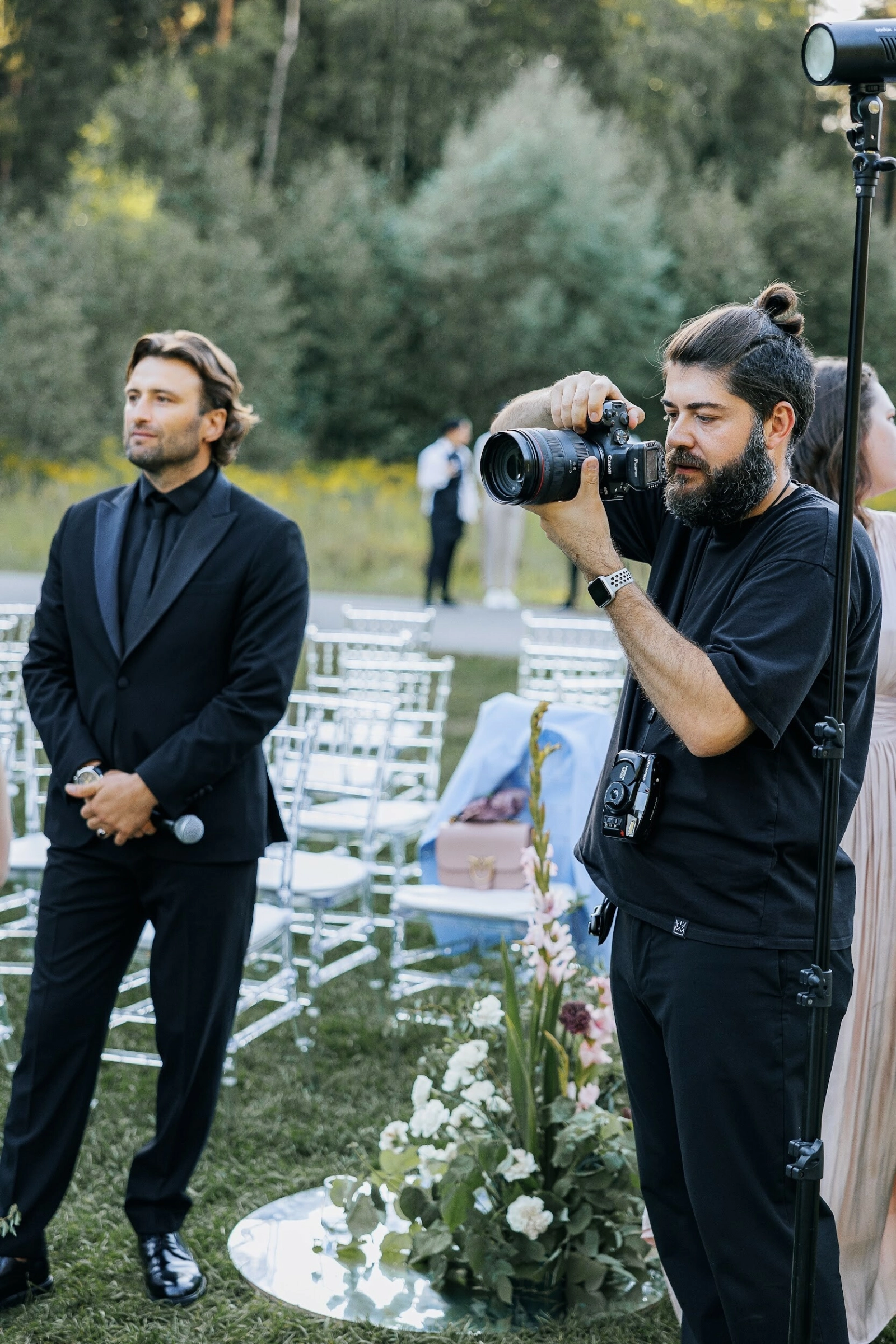 ведущий с микрофоном стоит рядом с фотографом на церемонии