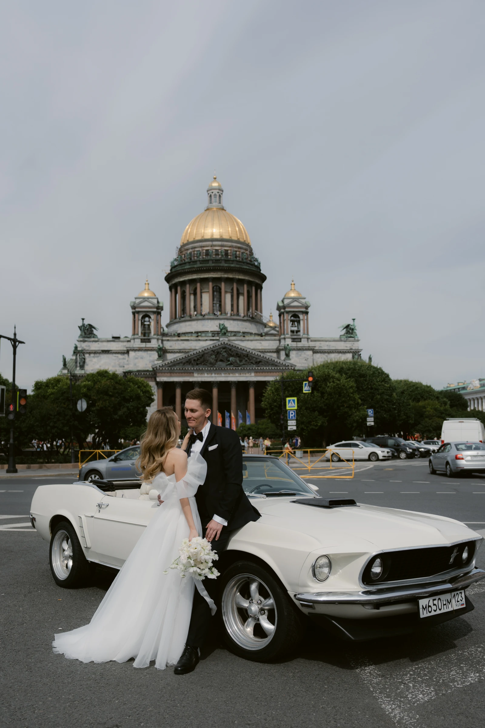 жених и невеста у белого ретро-кабриолета на фоне собора с куполом