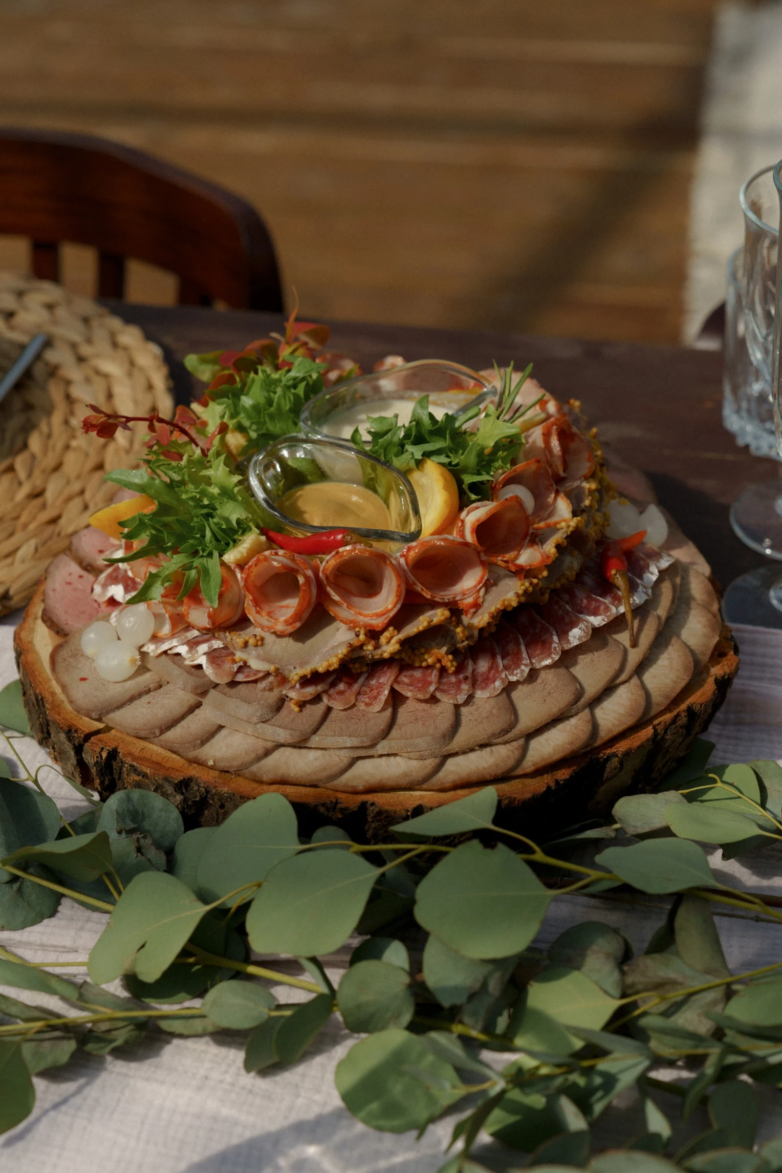 мясная тарелка с рулетиками и зеленью на деревянном спиле