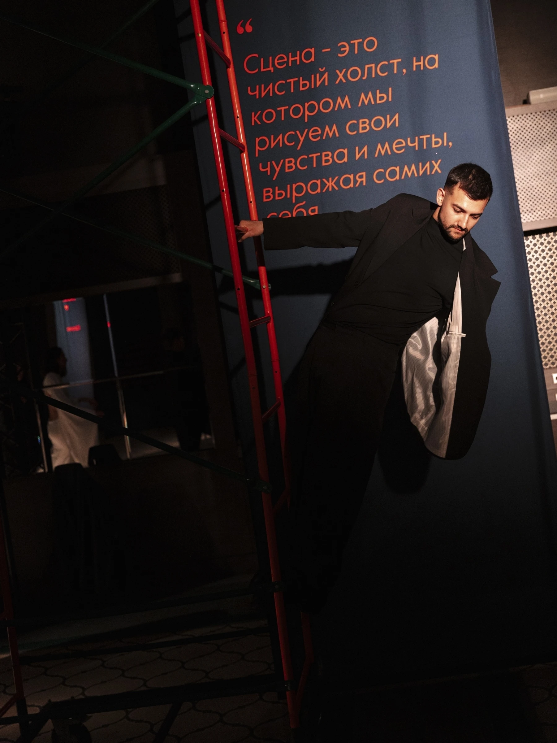 ведущий свадеб позирует на красной лестнице в студийной фотосессии