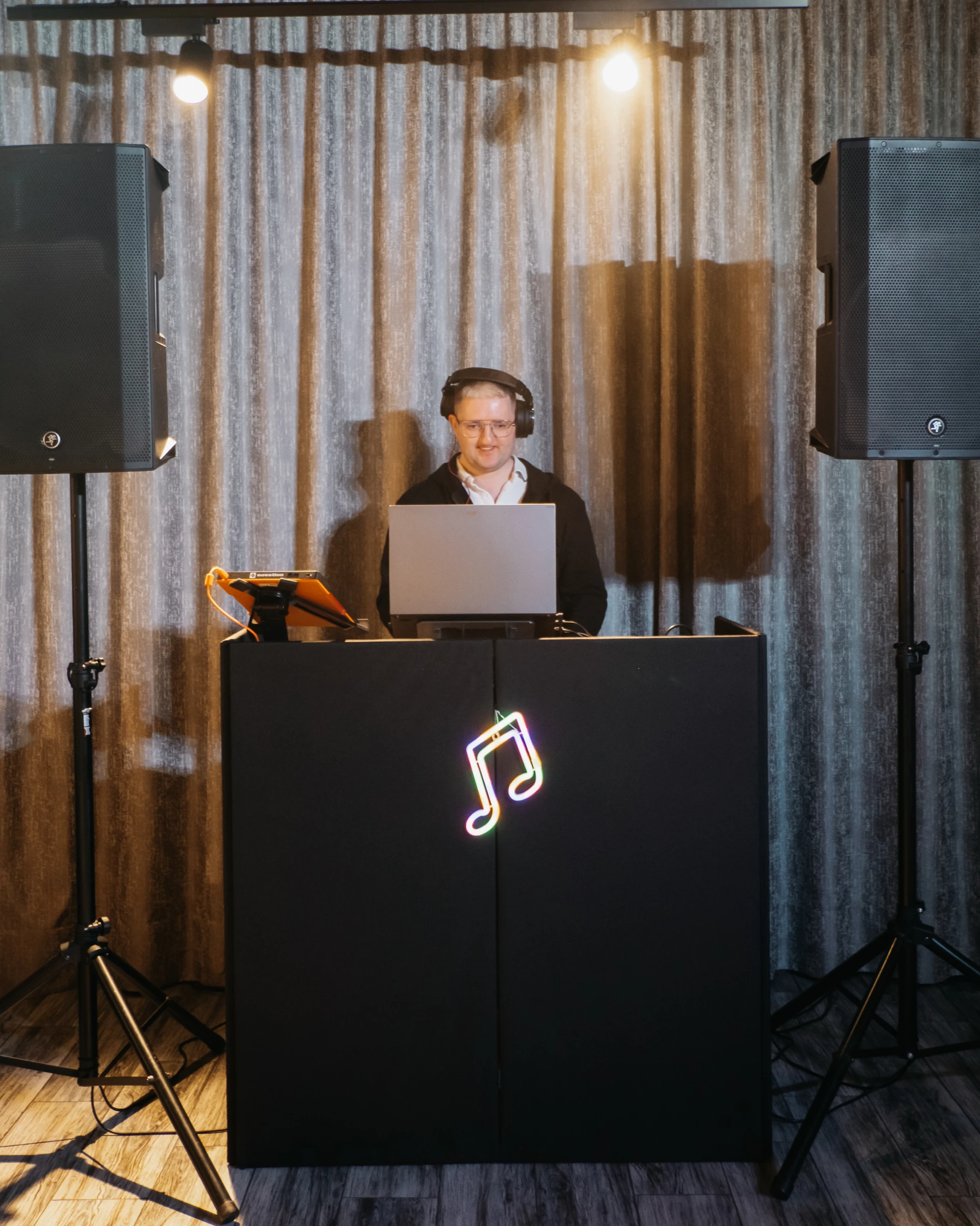 диджей за DJ-стойкой с ноутбуком и неоновой подсветкой на банкете