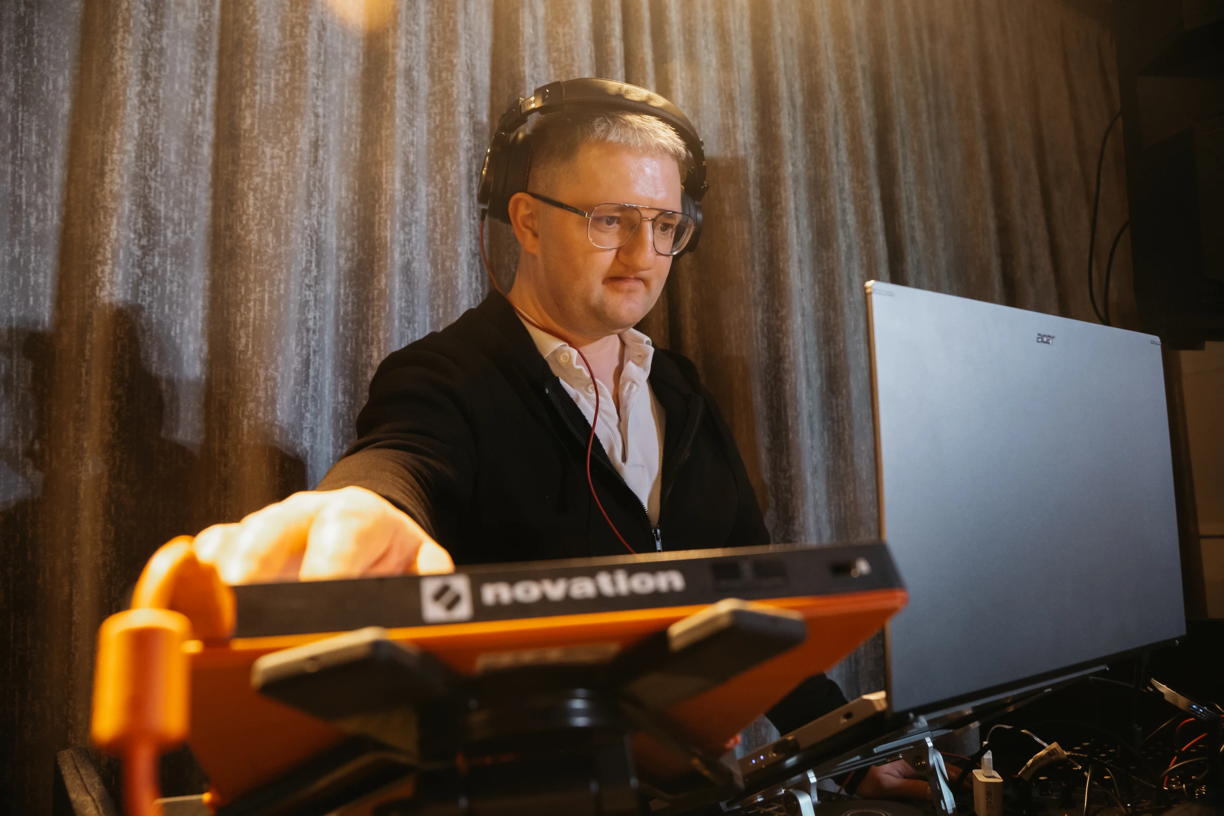 диджей работает с оранжевым MIDI-контроллером и ноутбуком на выступлении