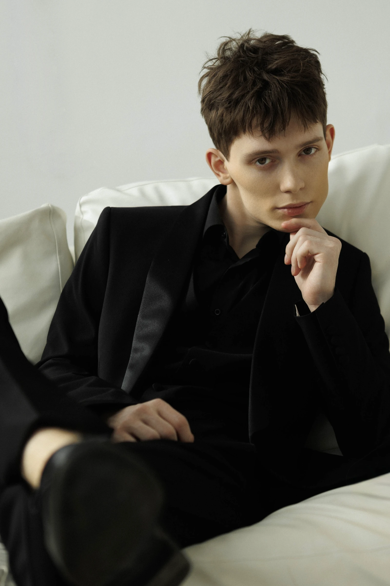 портрет жениха в чёрном костюме сидящего на светлом диване
