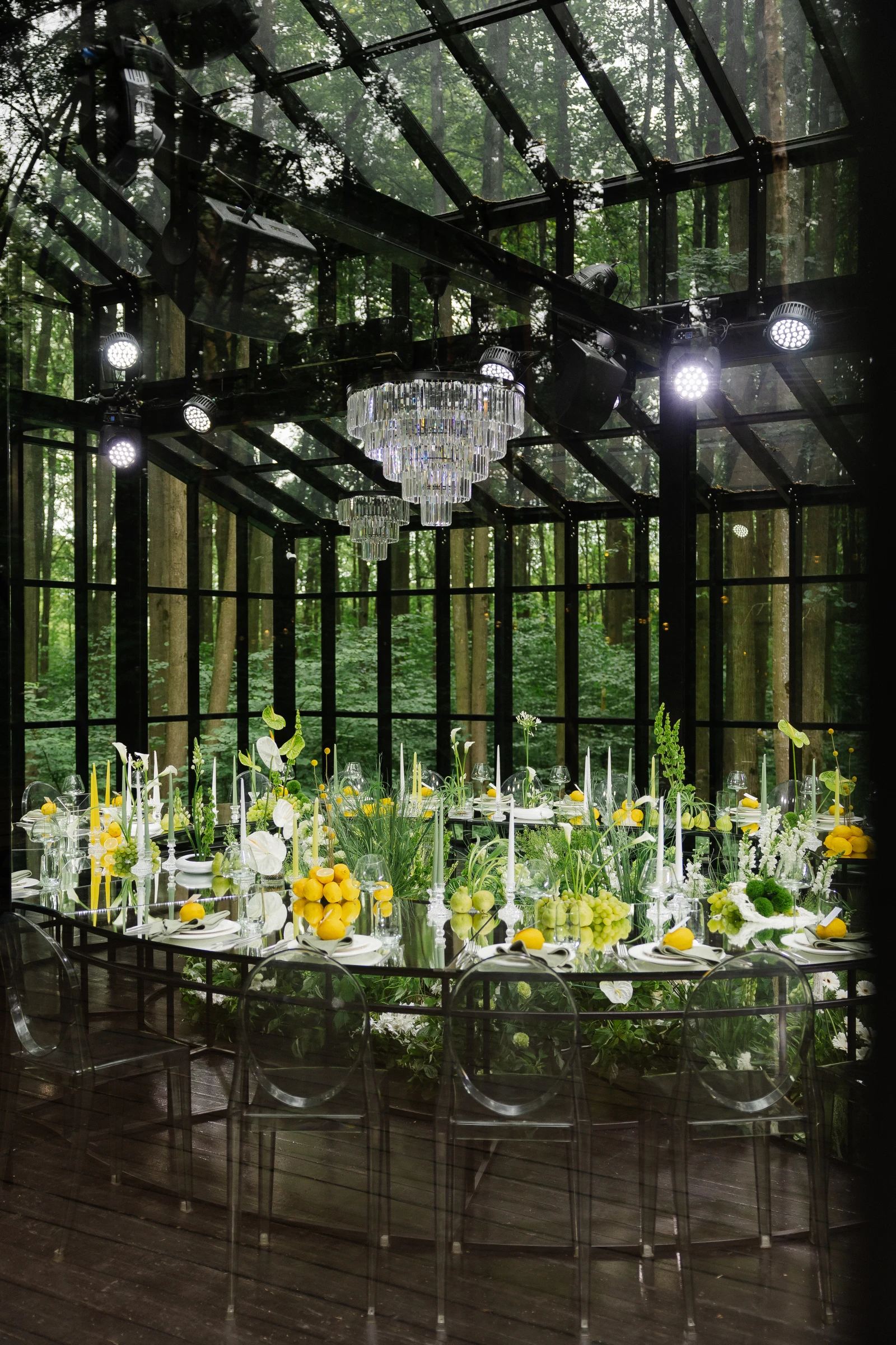 банкетный стол с прозрачными стульями свечами и лимонами в оранжерее