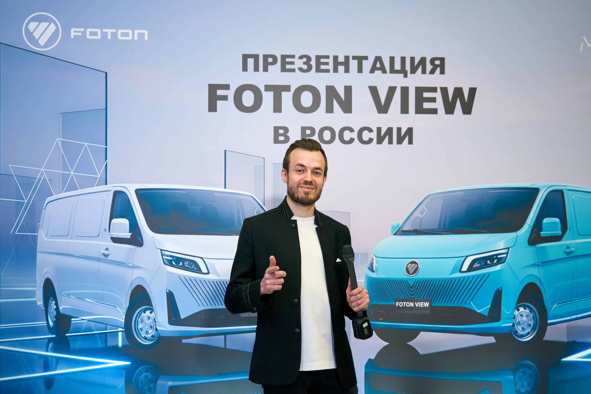 ведущий с микрофоном на презентации автомобиля на брендированном стенде