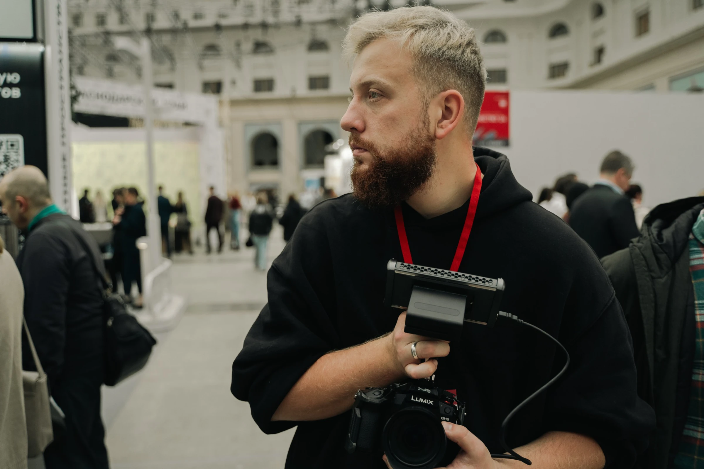 видеограф с камерой lumix на выставке смотрит в сторону