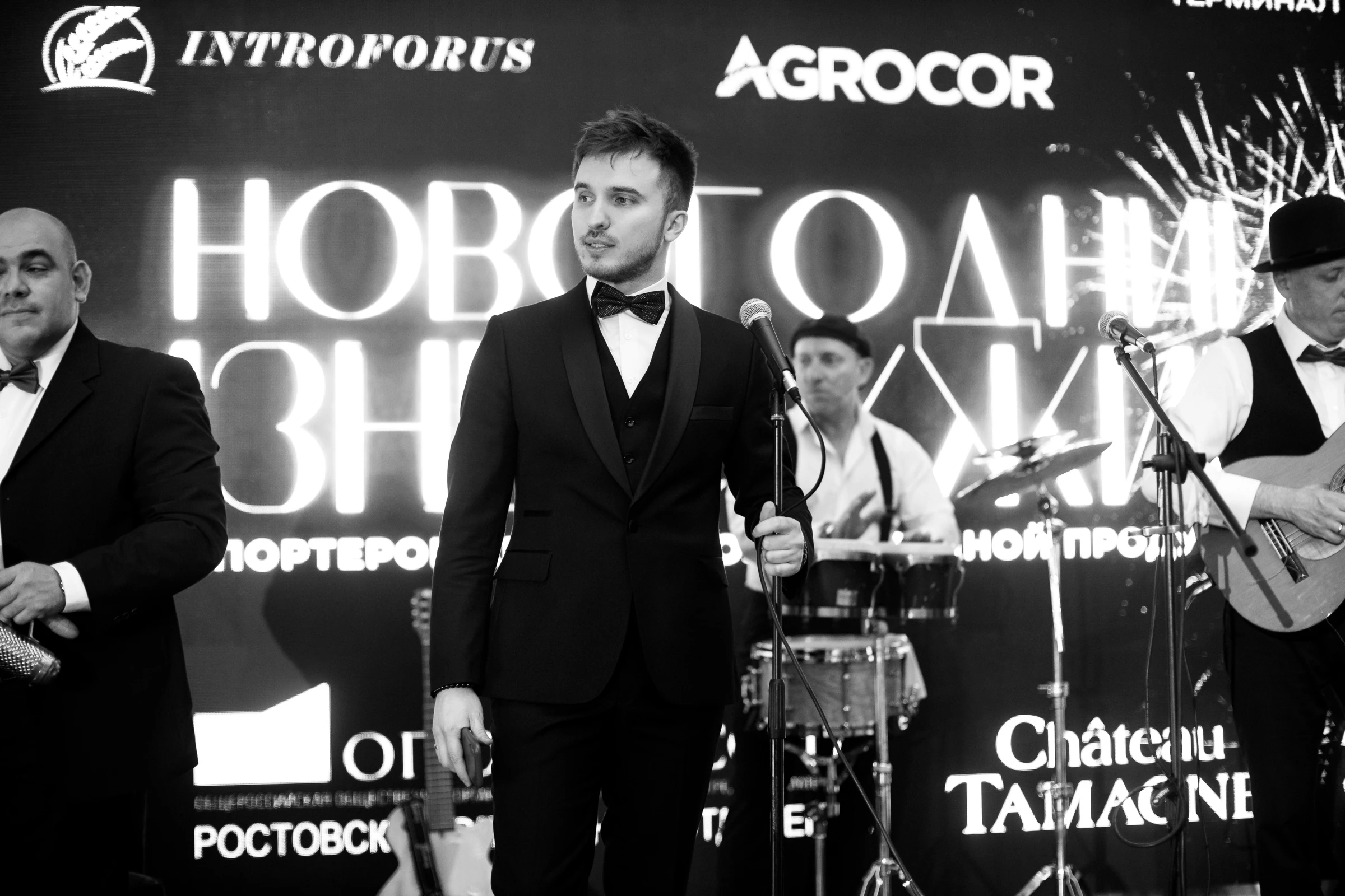 ведущий в смокинге с микрофоном на новогодней корпоративной сцене