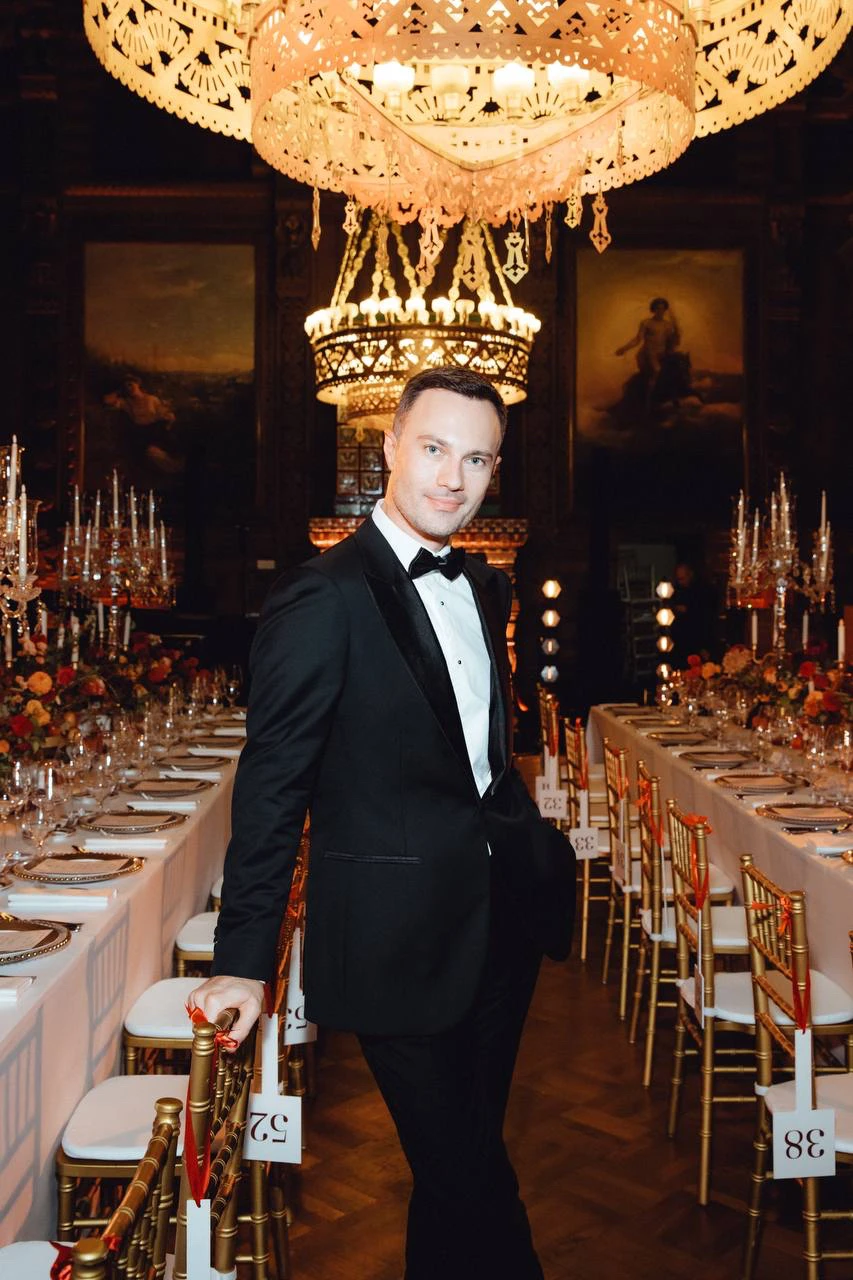 ведущий в смокинге в банкетном зале под люстрой