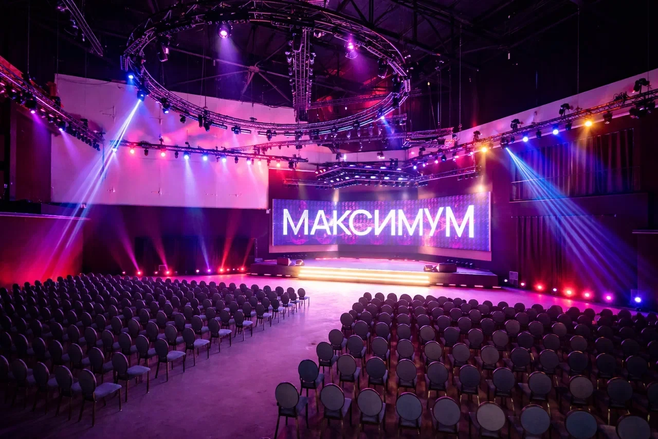 Зал с креслами и сценической подсветкой на мероприятии