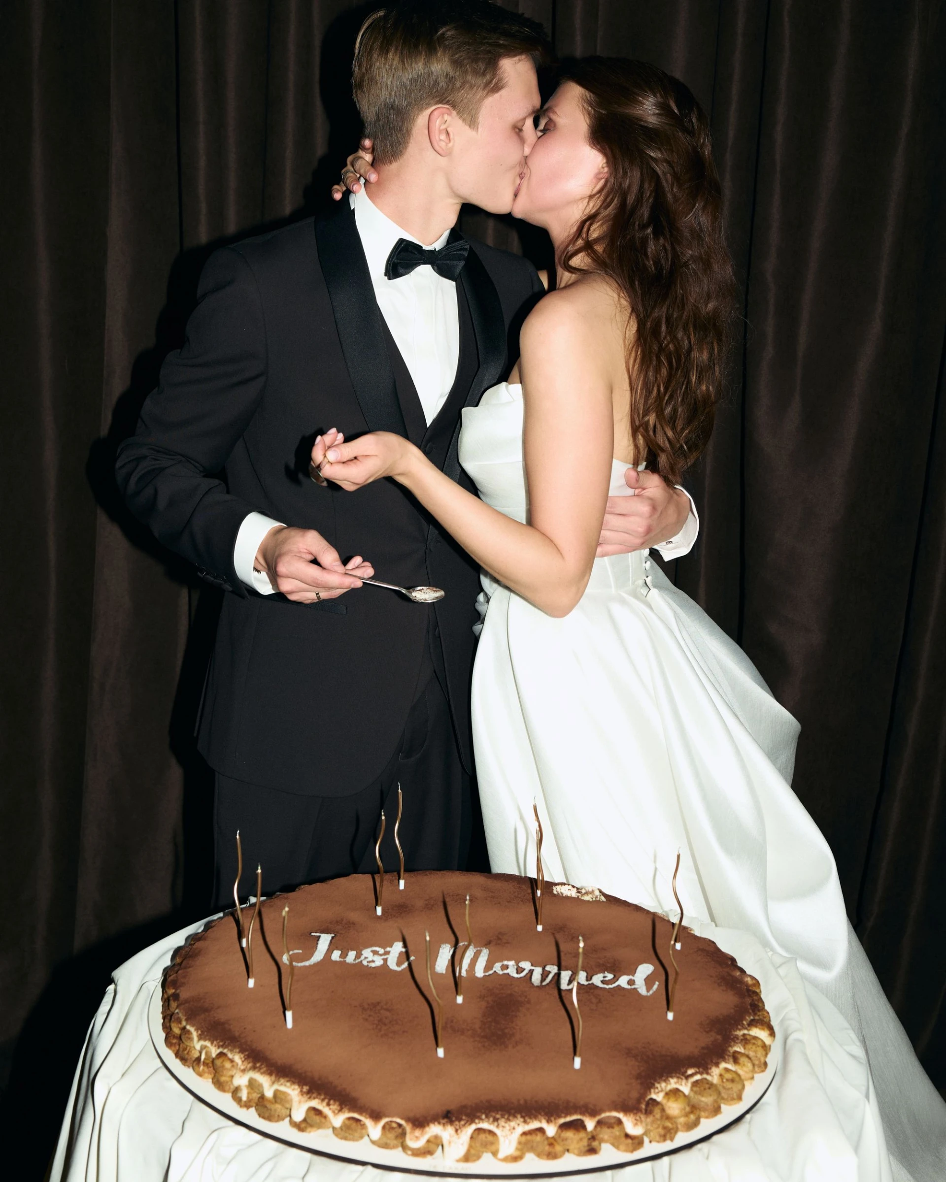 Жених и невеста целуются возле торта с надписью Just Married