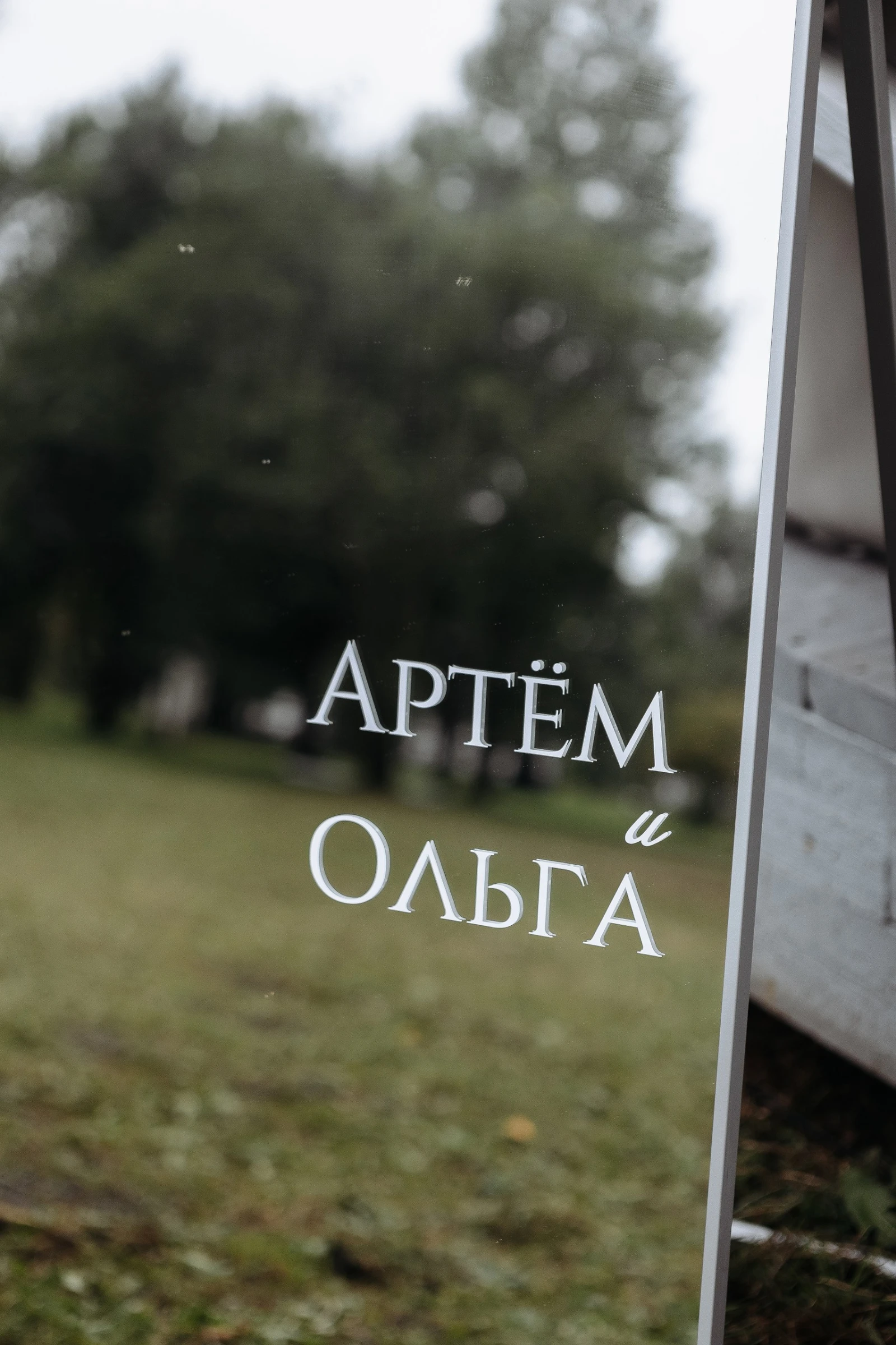 табличка с именами молодожёнов на фоне зелёного парка