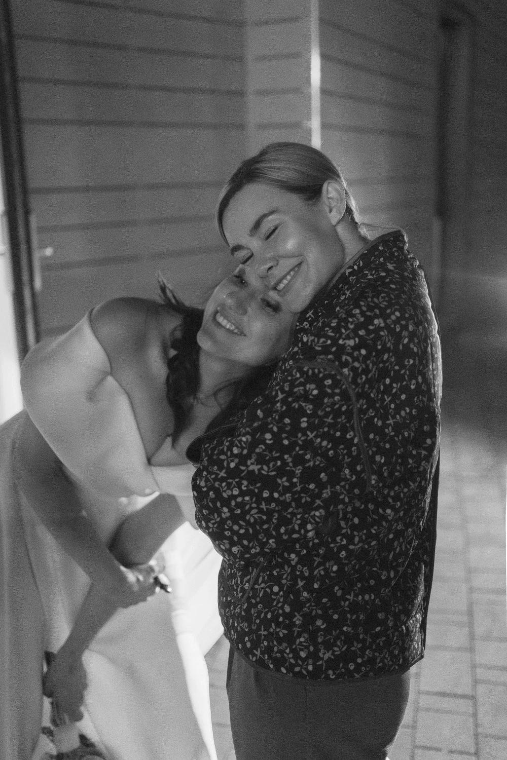 невеста нежно обнимает маму в чёрно-белом репортажном кадре коридора